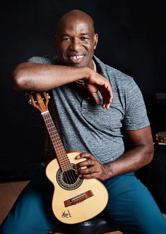Mestre Beiçola sorrindo, apoiado em um cavaquinho